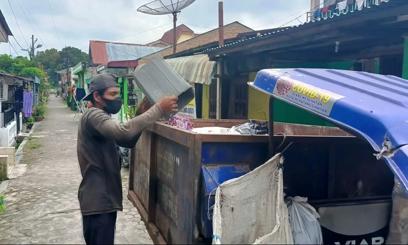  Ramadan Sibarani, parsampah atau tukang angkut sampah sedang mengangkut sampah warga di Jalan Enau 1, Desa Lestari Indah, Kecamatan Siantar, Kabupaten Simalungun. (Foto: PARBOABOA/Jeff Gultom)